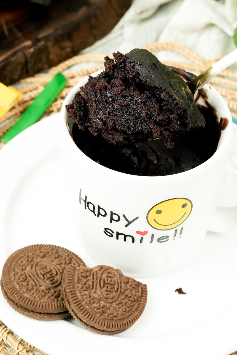 A spoonful of fluffy chocolate Oreo mug cake being lifted from a mug