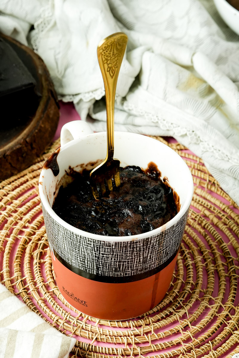 A gold fork standing in a freshly baked chocolate mug cake