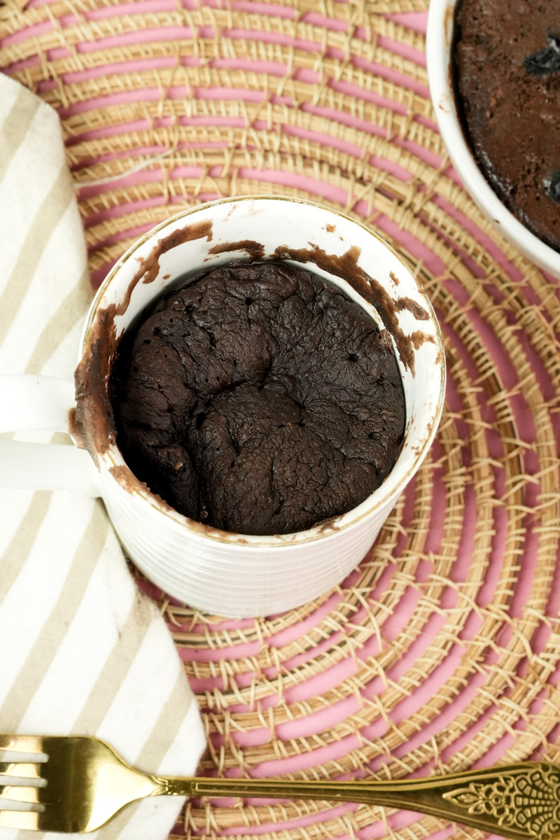 Top view of a fully baked chocolate protein mug cake in a white cup