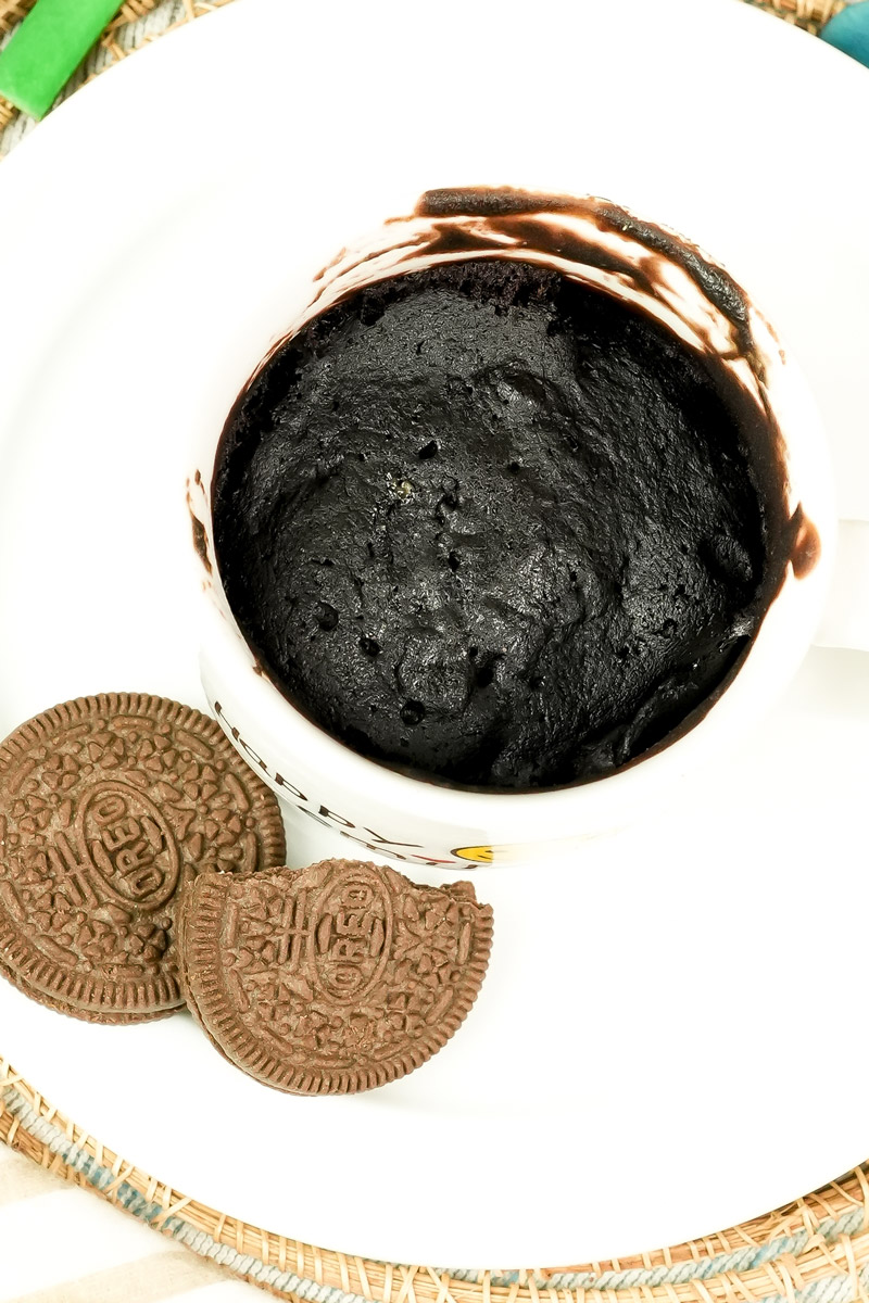 Top-down view of a moist Oreo mug cake next to chocolate cookies