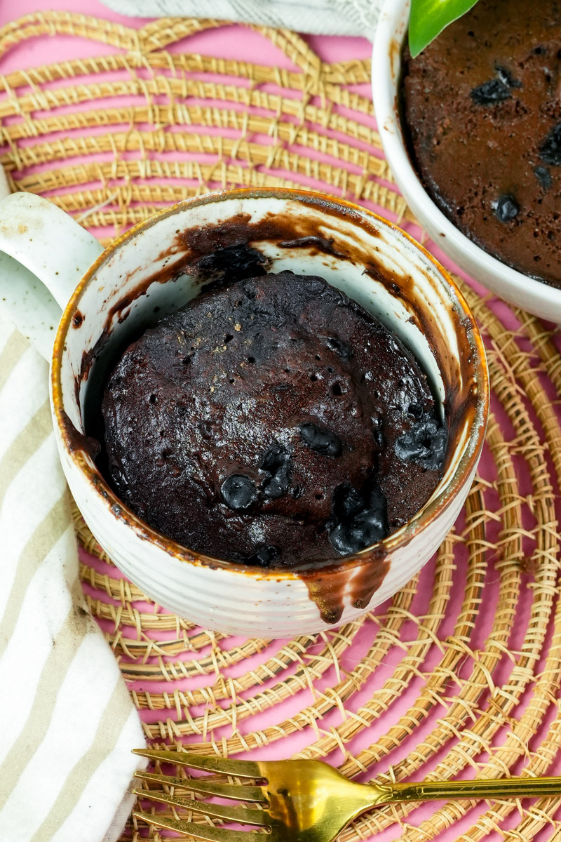 Overhead view of a moist chocolate mug cake in a white ceramic cup