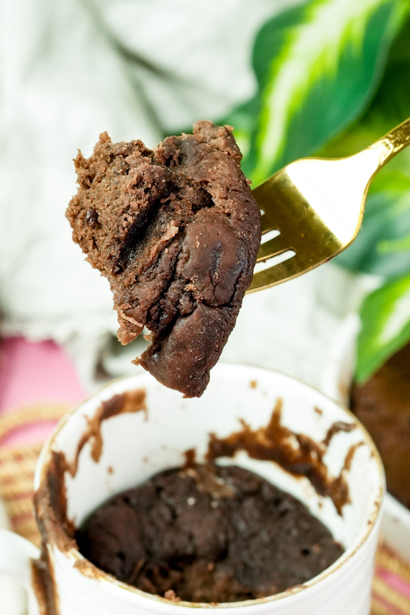 A gold fork holding a moist piece of chocolate protein cake