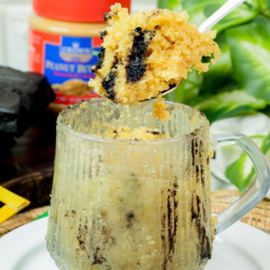 Bite-sized piece of peanut butter cake on a spoon over the mug