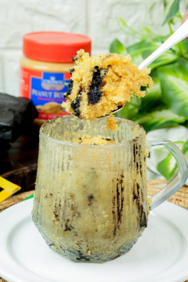 Bite-sized piece of peanut butter cake on a spoon over the mug