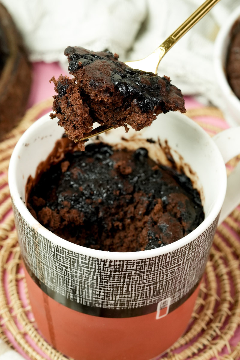 Bite-sized piece of chocolate mug cake on a gold spoon showing the texture