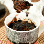 Steam rising from a piece of hot chocolate mug cake on a gold fork