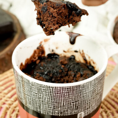 Steam rising from a piece of hot chocolate mug cake on a gold fork