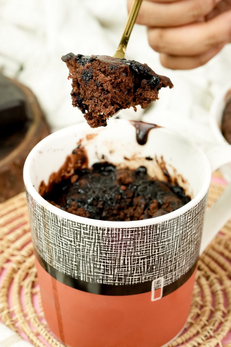 Steam rising from a piece of hot chocolate mug cake on a gold fork