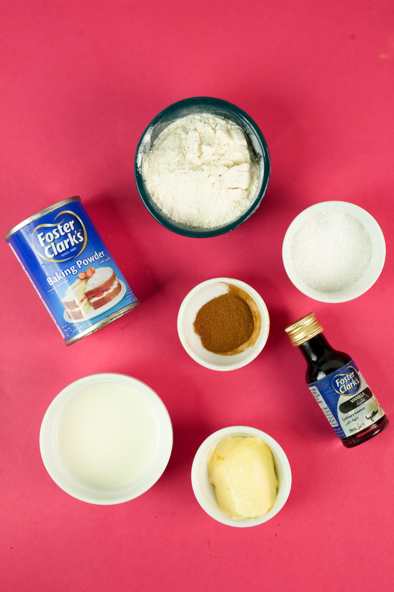 Flat lay of snickerdoodle mug cake ingredients including flour, sugar, cinnamon, milk, butter, and vanilla