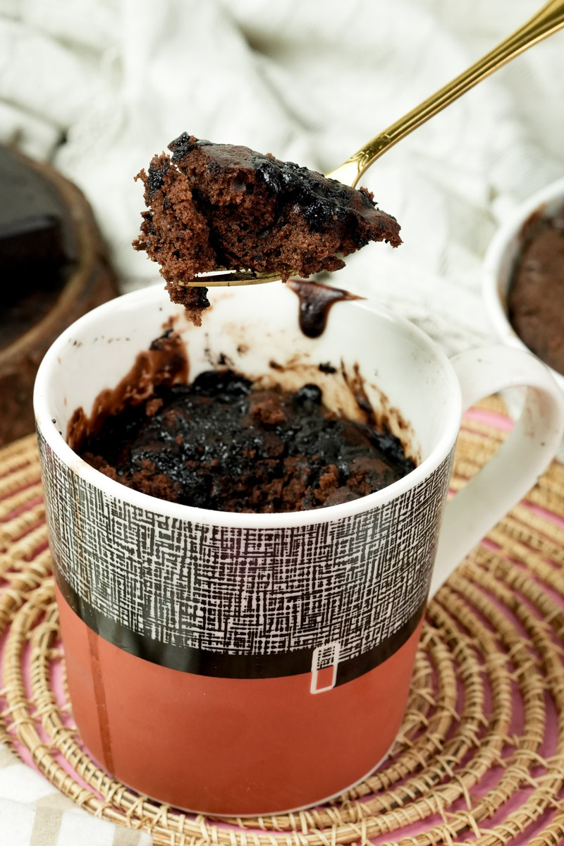 A spoonful of gooey chocolate mug cake held above the mug