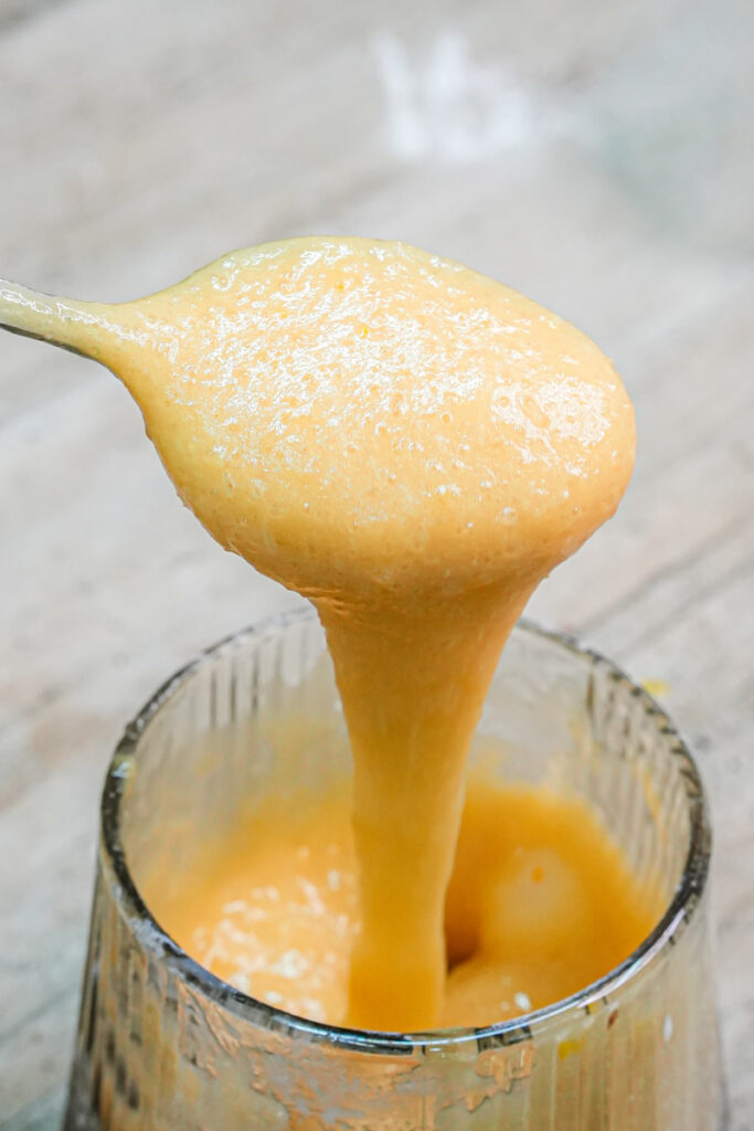 Close-up of thick, silky peanut butter cake batter dripping from a spoo